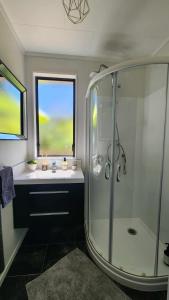 a bathroom with a glass shower and a sink at Beach House Matauri Bay in Matauri Bay