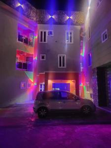 un coche aparcado frente a un edificio con luces coloridas en M View Hotel, en Benin City