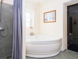 a white bathroom with a tub and a shower at 7 person holiday home in Grenaa in Grenå