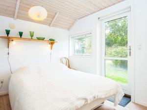 ein weißes Schlafzimmer mit einem Bett und einem Fenster in der Unterkunft Three-Bedroom Holiday home in Allingåbro 3 in Nørager