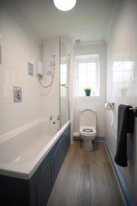 a bathroom with a bath tub and a toilet at Buckingham House - Charming 2-bedroom House with garden and parking in Buckingham