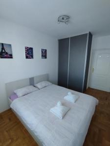 een slaapkamer met een wit bed met 2 kussens erop bij Apartman TOM Bijeljina in Bijeljina