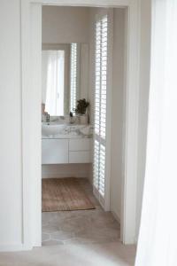 a white bathroom with a sink and a mirror at Verandah Retreat - A Beach House by the sea in Cowes