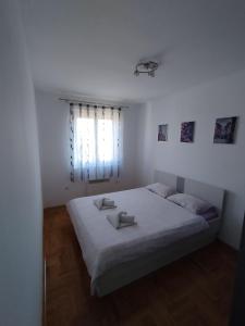 een witte slaapkamer met een groot bed en een raam bij Apartman TOM Bijeljina in Bijeljina