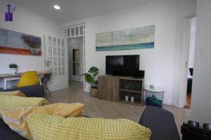 een woonkamer met een tv en een bank en stoelen bij Lisbon South Apartment in Lissabon