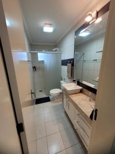 a bathroom with a sink and a toilet and a mirror at Nosso Ap em Bento in Bento Gonçalves +16 photos