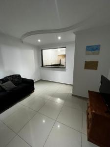 uma sala de estar com um sofá preto e uma janela em Casa de Irene em Cabo Frio