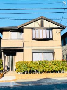 泉佐野JOY IN民宿两站关西机场一站奥莱，整租，提供机场接送服务,步行可达便利店、免税购物中心、药妆店的前面有灌木丛的棕褐色房子