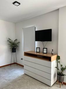 un soggiorno con TV su una parete bianca di DEPARTAMENTo EN COMPLEJO RESIDENCIAL CON COCHERA a Resistencia