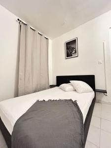 una camera da letto con un letto con lenzuola bianche e una finestra di Un Souffle de Vacances a Fort-de-France