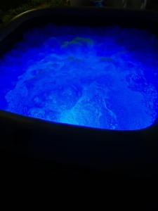 Un Souffle de Vacances في فورت-دو-فرانس: حوض استحمام أزرق مملوء بالماء في غرفة مظلمة