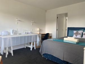 een slaapkamer met een bed, een wastafel en een bureau bij A private Large master room with en-suite in Auckland