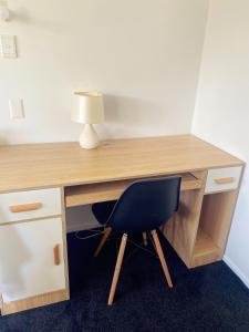 a desk with a chair and a lamp on it at A private Large master room with en-suite in Auckland