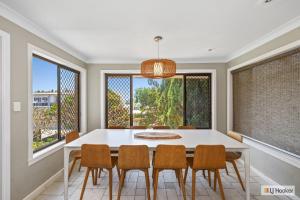 a dining room with a white table and chairs and windows at Kingscliff Ocean Vista in Kingscliff