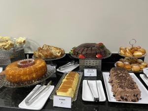 a table filled with different types of cakes and pastries at Asa Hotel in Piracicaba