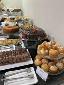 a table with many different types of cakes and pastries at Asa Hotel in Piracicaba