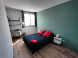 a bedroom with a bed with red pillows on it at Origami • Hippod. Enghien • 30 mn Paris in Eaubonne