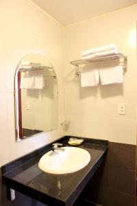 a bathroom with a sink and a mirror and towels at Bao Son Hotel in Ninh Lão