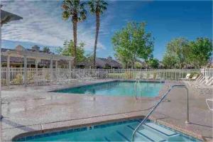 a swimming pool with a fence and palm trees at Luxurious fairway condo resort country club in Palm Desert