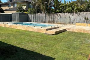 a swimming pool in a yard next to a fence at 81 Horace St WI FI and air conditioning in Shoal Bay