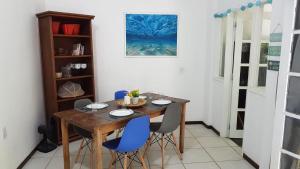 comedor con mesa de madera y sillas azules en Apartamento dos coqueiros Búzios, en Búzios