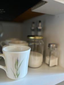 una tazza di caffè seduta su un bancone con barattoli di Deptos Punto Rivas Barrio Los Troncos a Mar del Plata