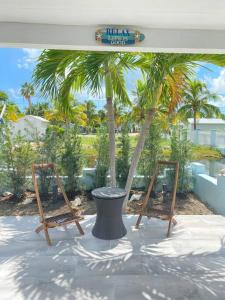 two wooden chairs sitting on a patio with palm trees at key Deer Retreat/direct gulf access/hot tub in Big Pine Key