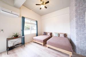 a bedroom with two beds and a brick wall at Panari in Miyako Island