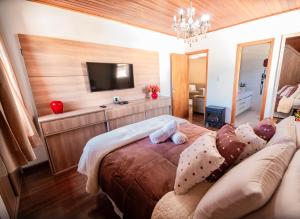 a bedroom with a couch and a flat screen tv at Luxuoso duplex no Capivari in Campos do Jordão