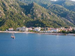 a boat in a body of water next to a mountain at Elite World Marmaris - Adult Only in Marmaris