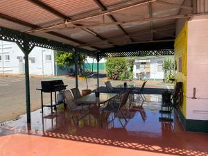 a patio with a table and chairs and a piano at Central Point Motel in Mount Isa