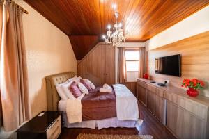 een slaapkamer met een bed en een televisie in een kamer bij Luxuoso duplex no Capivari in Campos do Jordão