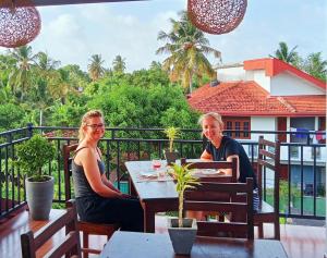 twee vrouwen aan een tafel op een balkon bij Ayubowan Homestay Katunayake in Katunayaka