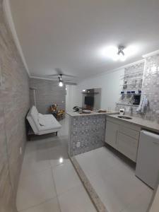 a large white kitchen with a sink and a chair at Apartamento Aconchegante in São Lourenço