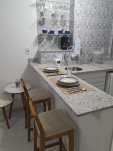 a kitchen with a counter with a table and chairs at Apartamento Aconchegante in São Lourenço