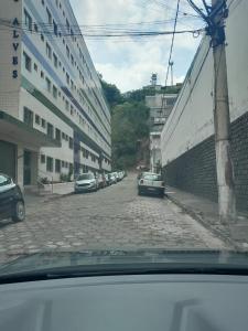uma rua com carros estacionados ao lado de um edifício em Apartamento Aconchegante em São Lourenço