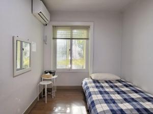 um quarto com uma cama, uma mesa e uma janela em Hongdae Cheese Guesthouse em Seul