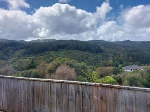 a view of a mountain with a fence and trees at A room in Riverstone Terraces with views - Homestay in Upper Hutt
