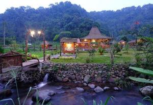 Ein Resort mit einem Bach und einem Gebäude mit Beleuchtung in der Unterkunft Rumah Lembah Bogor 