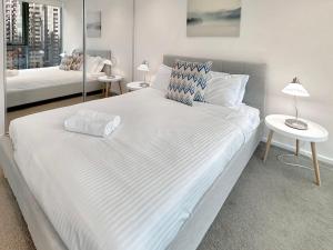 a large white bed in a room with two tables at Stunning 2-Bedroom Oasis in the Heart of Southbank in Melbourne