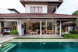 a villa with a swimming pool in front of a house at Sari Temuku Villa in Seminyak