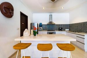a kitchen with a white counter and two wooden stools at Sari Temuku Villa in Seminyak