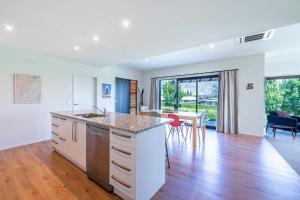 an open kitchen and living room with a table and chairs at Hoheria Mountain Lodge in Wanaka
