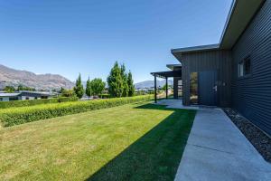 a house with a green lawn next to a building at Hoheria Mountain Lodge in Wanaka