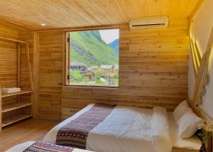 a bedroom with a bed in a wooden room with a window at Meo Vac Valley in Mèo Vạc +104 photos