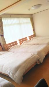 two beds in a bedroom with a window at ゲストハウス西金沢Smile&smile in Kanazawa