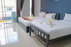 Dos camas en una habitación de hotel con flores. en โรงแรมศุภชัย อินน์, en Ban Ba Ngan