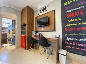Una habitación con un escritorio y un televisor en la pared. en Araras Apart Service I, en Caldas Novas