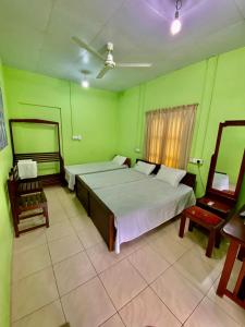 a bedroom with two beds and two chairs in it at Green Villa in Oluvil
