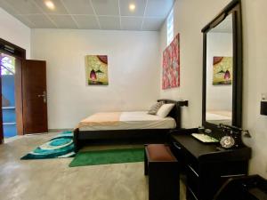 a bedroom with a bed and a desk and a mirror at Green Villa in Oluvil
